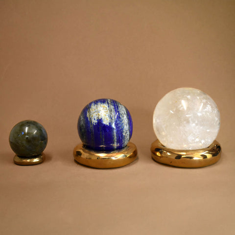 Three crystal balls on gold stands against a beige background