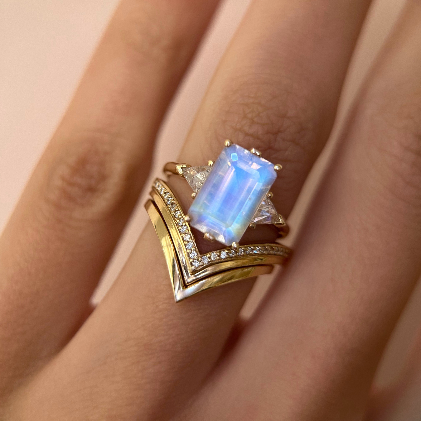 Gold ring with a bluish purple moonstone gemstone on a hand against a light background