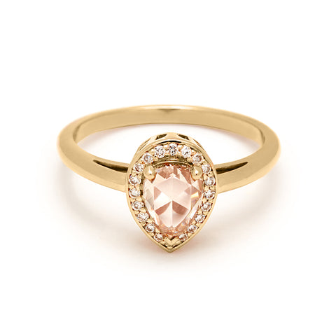 An engagement ring with a pear shape champagne diamond center stone surrounded by a white diamond pave halo set in yellow gold.