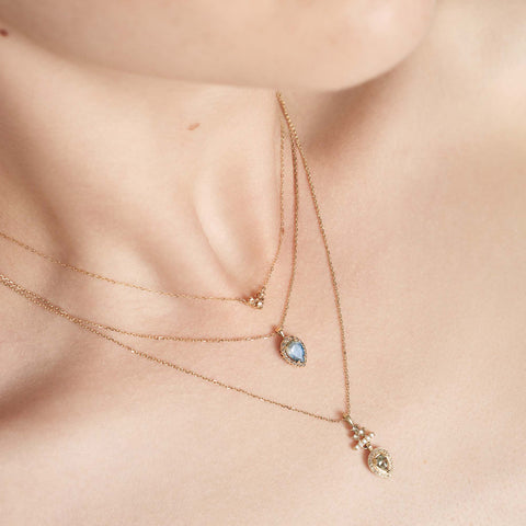 A 16" chain necklace with three black diamonds in the shape of an arrow at the base set in yellow gold stacked above two amulet halo necklaces on a light-complexion models neck., White Gold, Rose Gold, Yellow Gold 3