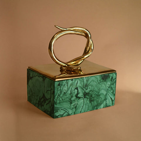 A malachite box with a bronze lid featuring a snake design on a beige background
