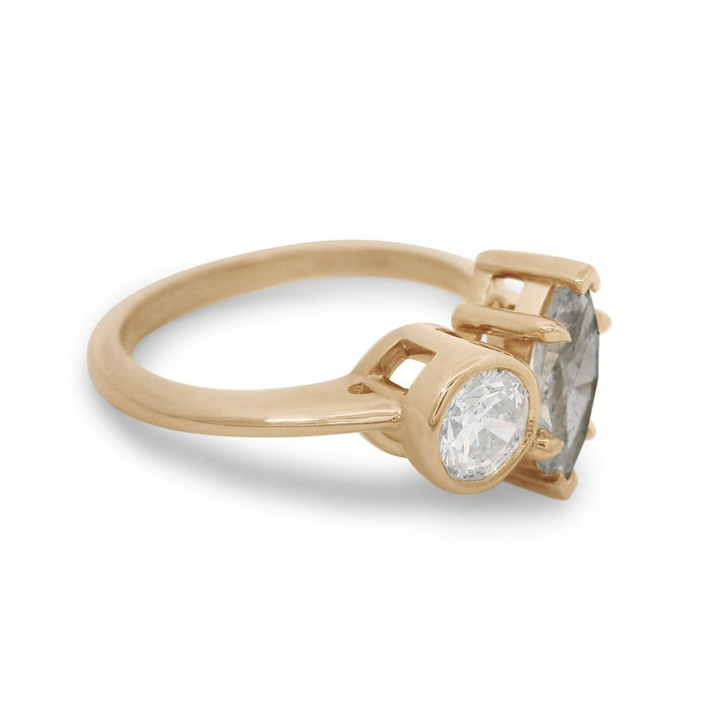 A yellow gold toi et moi engagement ring featuring a white round diamond and a grey marquise diamond on a white background