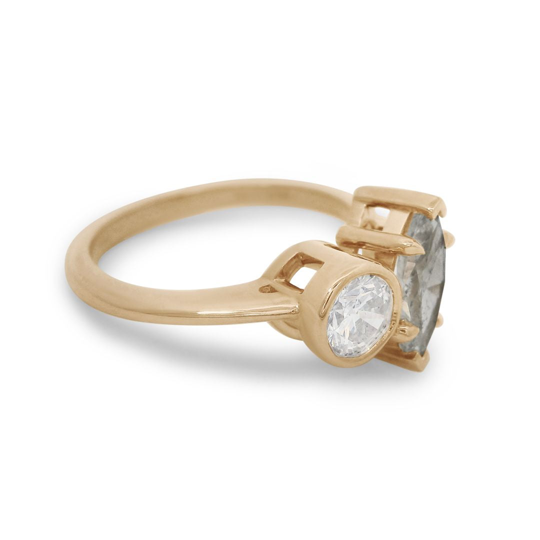 A yellow gold toi et moi engagement ring featuring a white round diamond and a grey marquise diamond on a white background