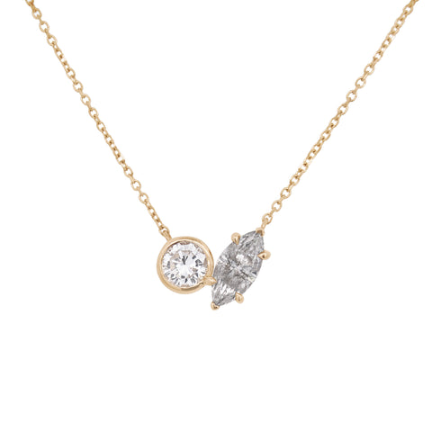 A yellow gold toi et moi necklace featuring a round white diamond and a marquise grey diamond on a white background 