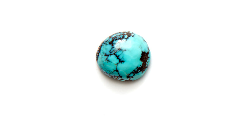 Turquoise cabachon on a flat surface and white background
