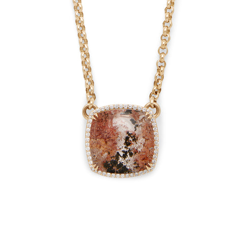 A cushion shaped quartz charm with a desert like scene in a bezel setting with claw prongs and a white diamond halo set in yellow gold on a yellow gold chain.