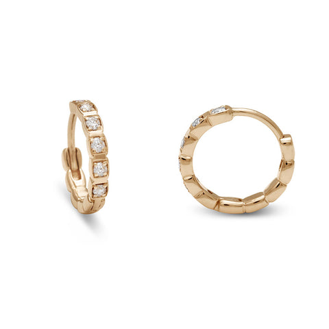A gold pair of huggie hoops with white diamonds set in yellow gold one earring turned to the side. 2