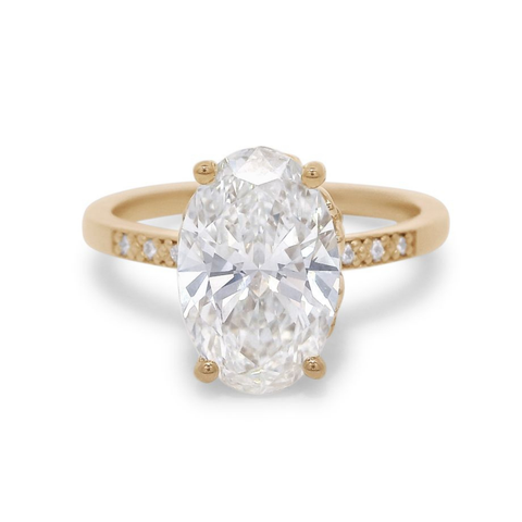 A 2.11 ct white oval lab diamond engagement ring featuring pave diamonds on the band set in 14kt yellow gold.