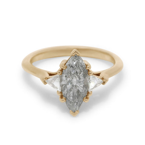 Three stone ring featuring a marquise cut grey diamond with white trillion diamond side stones set in yellow gold. 