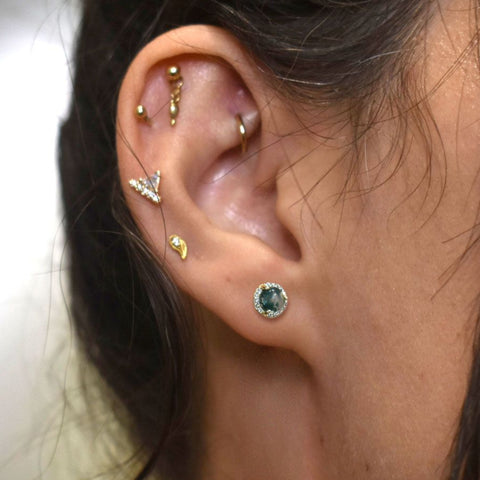 Close-up of an ear with multiple gold and silver earrings including a moss agate cabochon stud.  2