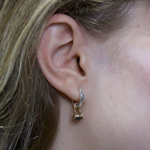 A picture of a silver hoop earring with a gold drop detail and inverted black rutile quartz gemstone on a woman's ear.  2