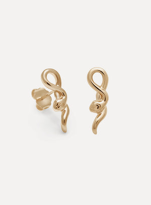 A pair of 14k yellow gold small serpent stud earrings set in front of a pink/white background.