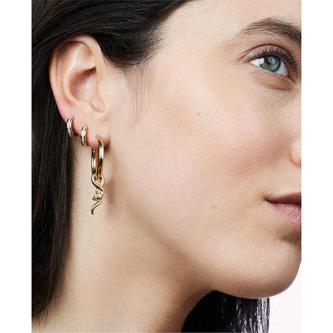 A single hoop earring with a serpent charm at the bottom set in yellow gold on a light complexion model's ear with two diamond dusted hoops. 4