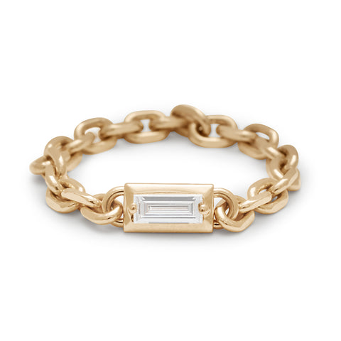 A band with a bezel set white diamond baguette in a yellow gold chain setting.