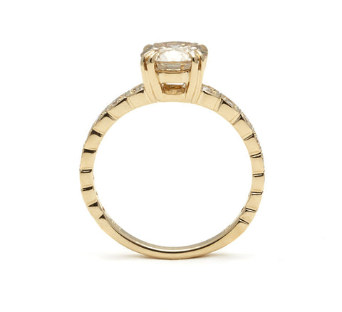 Side view of a solitaire ring with a brilliant cut champagne diamond with white diamond pave around the band set in yellow gold. 2