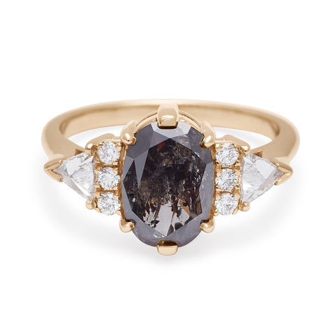 An oval shape 1.38ct grey diamond center stone ring with three round white diamonds on either and two white diamond trillions on the outer edges of each side set in yellow gold.