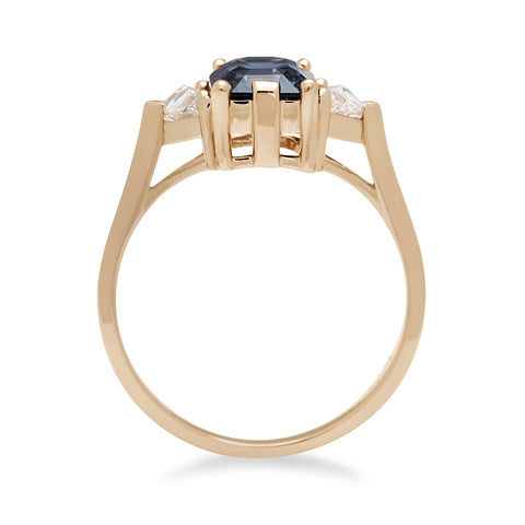 Side view of a three stone engagement ring with an emerald cut and emerald shape grey spinel center stone with two white diamond trillion side stones set in yellow gold., Yellow Gold 2