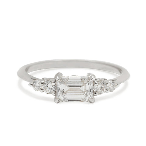 A ring with an emerald cut and shaped white diamond center stone with two round white diamonds on either side set in white gold., White Gold 6