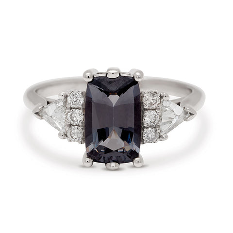 A emerald shape grey spinel center stone ring with three round white diamonds on either and two white diamond trillions on the outer edges of each side set in white gold.