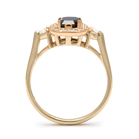 Side view of a three stone engagement ring with an emerald cut and emerald shape black diamond center stone surrounded by a white diamond pave halo with two white diamond trillion side stones set in yellow gold., Yellow Gold 3