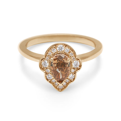 A pear shaped champagne diamond ring set in a halo of white diamonds and in yellow gold.