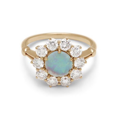 A ring with a round opal center stone surrounded by round white diamonds set in a yellow gold band.