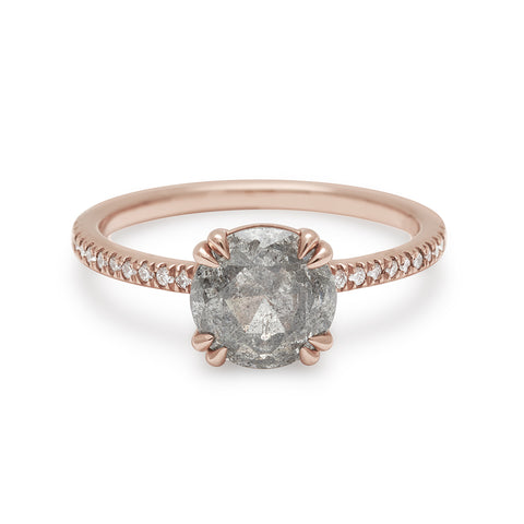 A solitaire round grey diamond ring with double claw prongs with white diamond pave on the band set in rose gold.