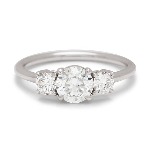 A three stone engagement ring with a round shape white diamond center stone with two round white diamond stones set in white gold.