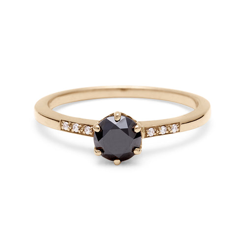 A solitaire ring with a round black diamond with white diamond pave on either side set in yellow gold.
