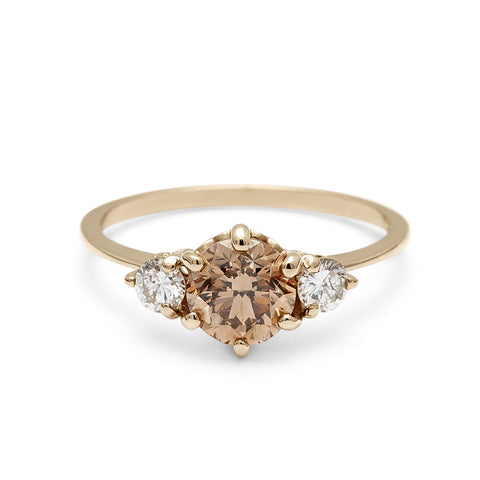 A three stone engagement ring with a round shape champagne diamond center stone with two white diamond round side stones set in yellow gold., Yellow Gold