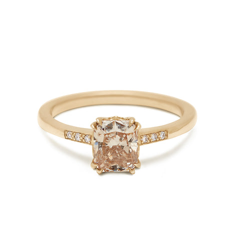 A solitaire ring with a cushion cut 1.00ct champagne diamond with white diamond pave on either side set in yellow gold.