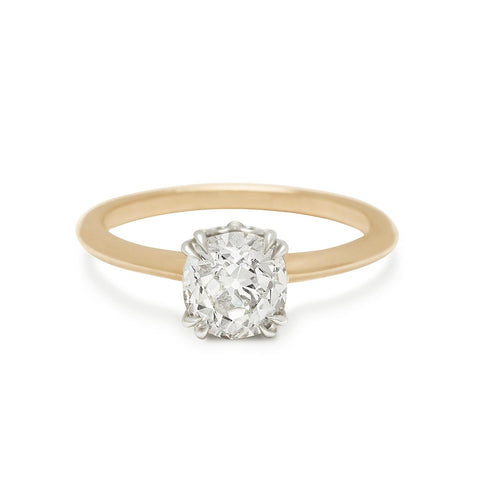 A solitaire ring cushion cut white diamond set in white gold basket and a knife edge yellow gold band.