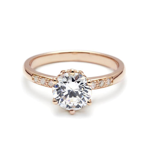 A solitaire ring with a round brilliant cut white diamond with white diamond pave on either side set in rose gold., Rose Gold 7