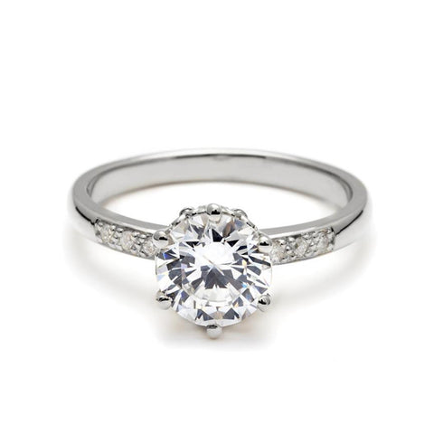 A solitaire ring with a round brilliant cut white diamond with white diamond pave on either side set in white gold., White Gold