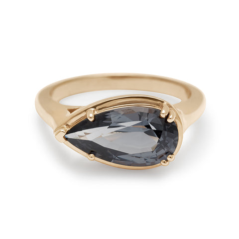 A solitaire ring pear shaped grey spinel set in yellow gold.