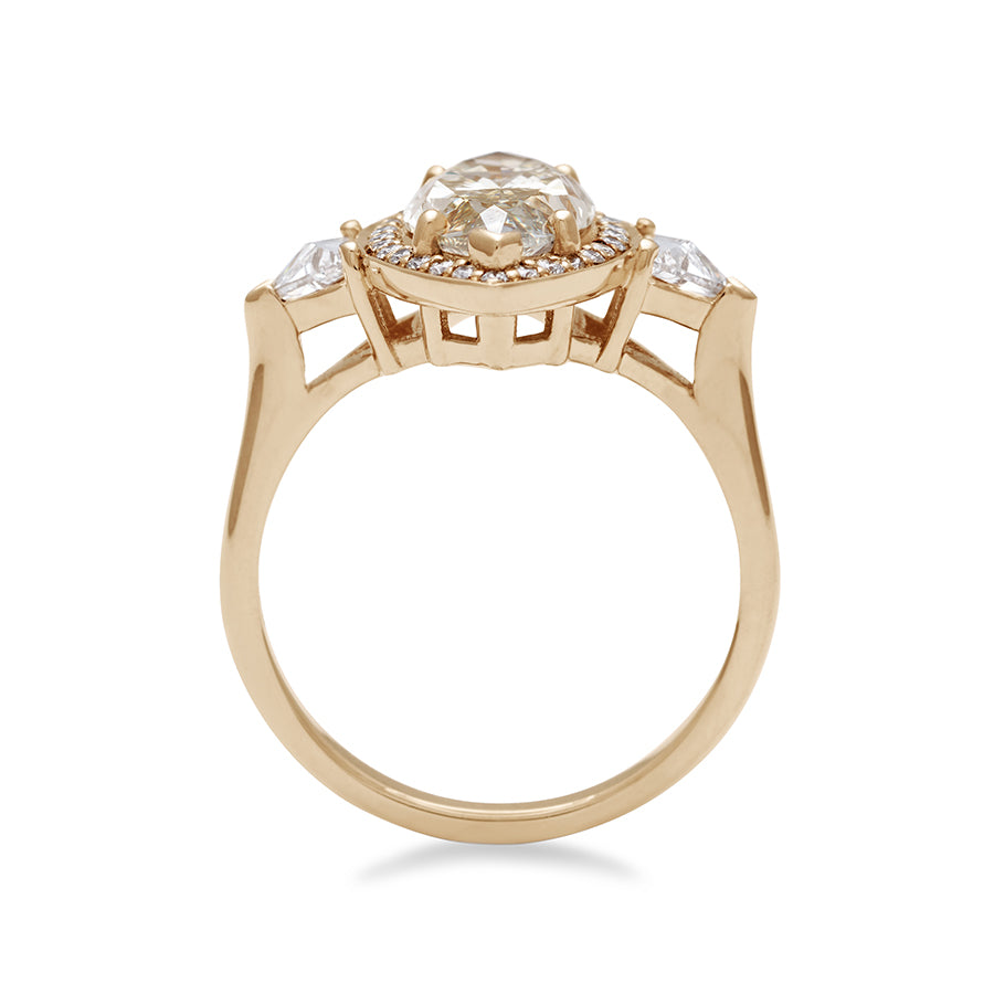 Side view of a three stone engagement ring with a marquise shape champagne diamond center stone surrounded by a white diamond pave halo with two white diamond trillion side stones set in yellow gold.