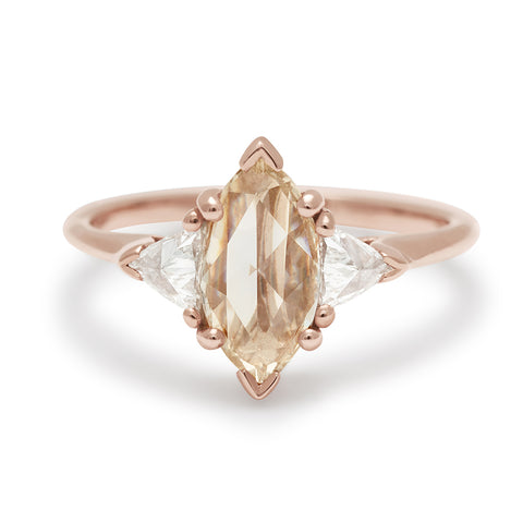 A three stone engagement ring with a marquise shape 0.85ct champagne diamond center stone with two white diamond trillion side stones set in rose gold.