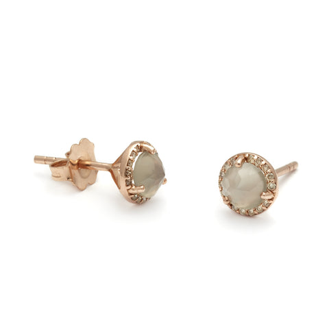 A pair of medium grey moonstone center stone earrings with a halo of champagne diamond set in rose gold one earring angled.