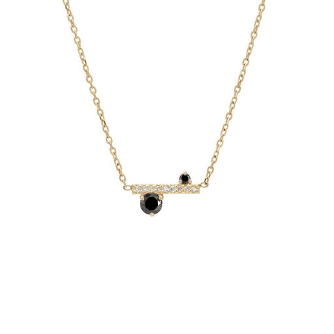 A straight line of white diamond pave with black diamond accent stones on either side set in a yellow gold necklace chain.
