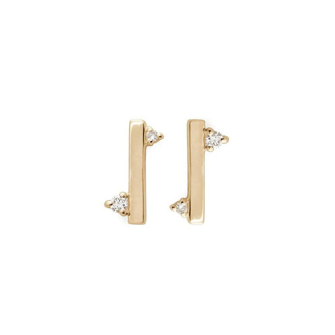 A pair of straight line earrings with white diamond accent stones on either side set in yellow gold.
