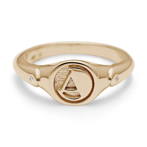 A monogrammed signet ring with an "A" on the front and two white diamond accents on either side and set in yellow gold.