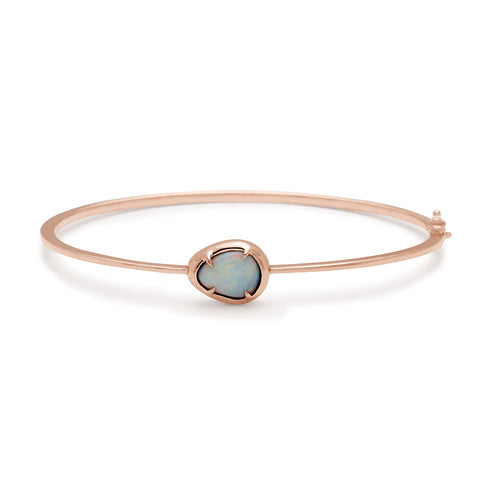 A bracelet with an opal center stone set in bezel with claw prongs all set in rose gold.