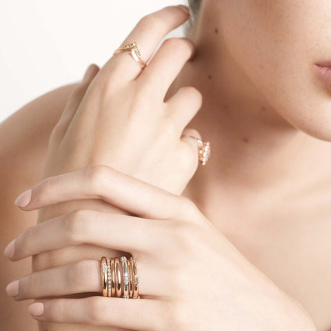 Three straight band with 5 clusters white diamond band set in yellow gold on a light-complexion models ring finger. 4