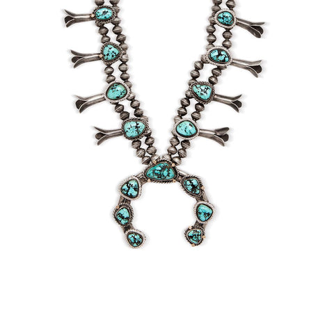 Zoomed in view of a turquoise stone squash blossom necklace set in sterling silver.