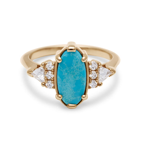An oval shape turquoise center stone ring with three round white diamonds on either and two white diamond trillions on the outer edges of each side set in yellow gold.