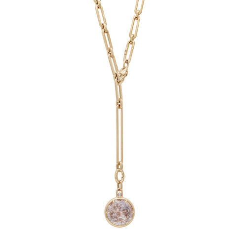 A quartz charm with a desert like scene in a bezel setting with claw prongs set in yellow gold with white diamond accent stone on a mixed link yellow gold chain.