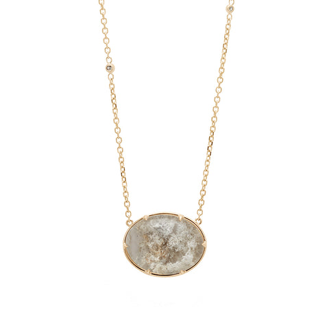 An oval quartz charm with a desert like scene in a bezel setting with claw prongs set in yellow gold on a yellow gold chain with grey diamonds on it.