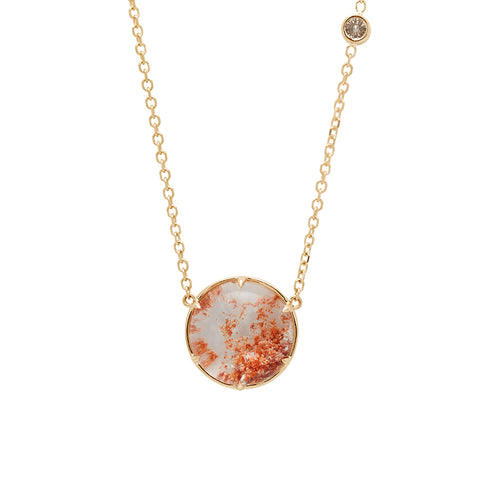 A round quartz charm with a desert like scene in a bezel setting with claw prongs set in yellow gold on a yellow gold chain with a champagne diamond on it.