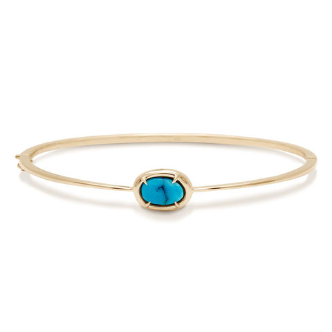 A bracelet with a bezel set turquoise stone with claw prongs set in yellow gold.