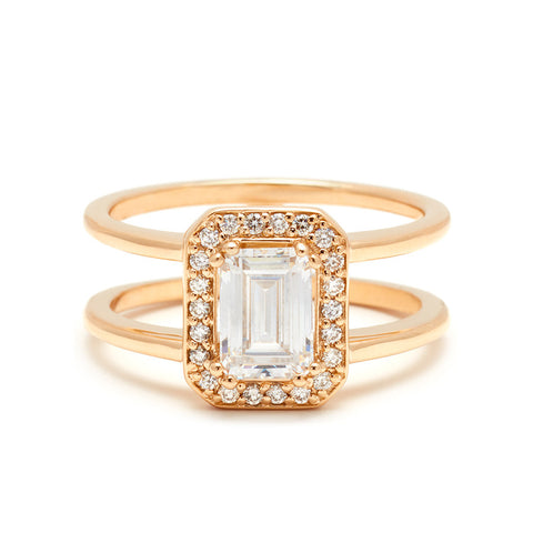 A double banded engagement ring with a white diamond emerald cut diamond surrounded by a white diamond halo set in yellow gold.